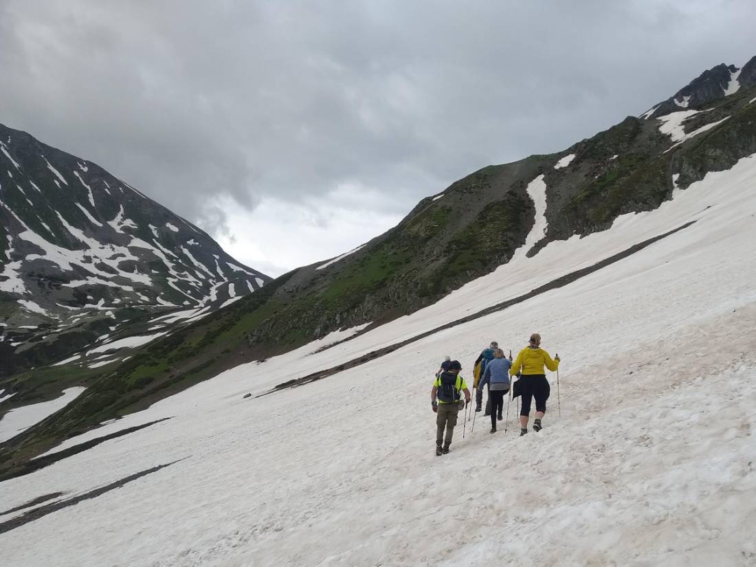 Hikers walk on a patch of snow on the Transcaucasian Trail