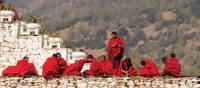 Bhutanese monks socialise along the monastery wall | Liz Light